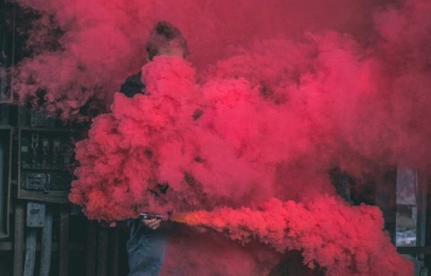 photo of man surrounded by red smoke